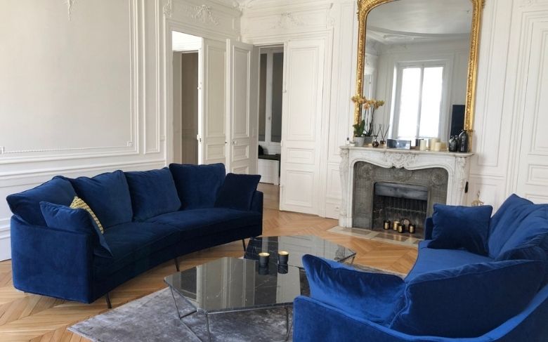 salon avec canapés bleu cheminée et grand miroir